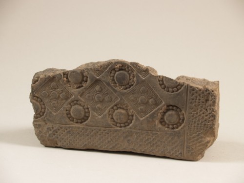 Fragment, bouwkeramiek, van grijs aardewerk met gestempeld patroon van o.a. cirkels en noppen